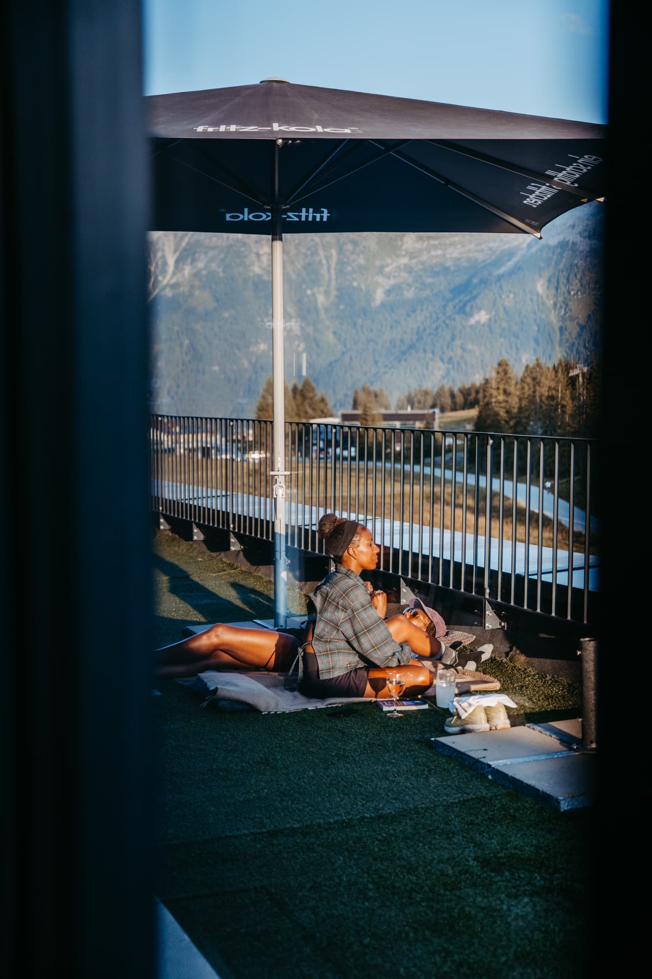 Person relaxing under umbrella on mountain lodge terrace